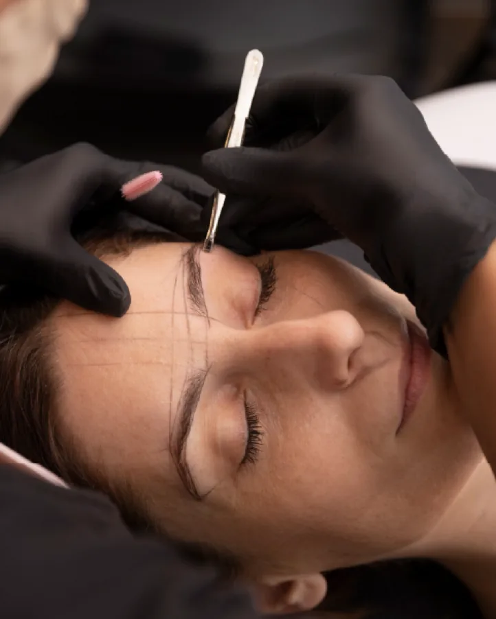 Samanttha marcando o desenho da sobrancelha de uma cliente com lápis dermatográfico durante a etapa de mapeamento facial
