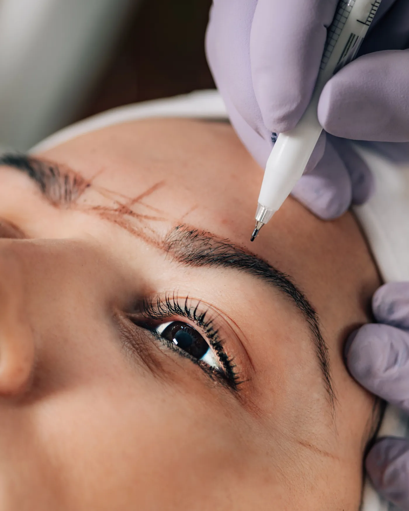 Aplicação de micropigmentação fio a fio na sobrancelha com dermógrafo, em vista aproximada do rosto