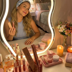 Penteadeira iluminada com espelho, produtos de beleza organizados em tons nude e rosé